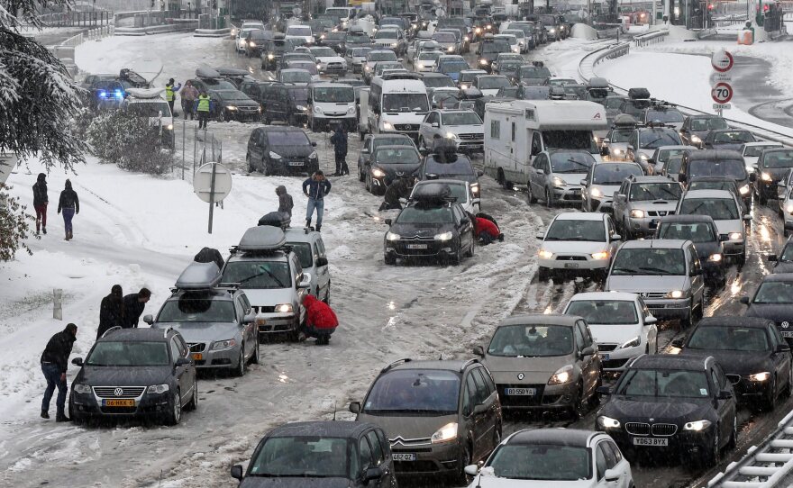 Drivers park to put on snow chains in the middle of a massive traffic jam in the Savoie region of France. Thousands of motorists are stranded for a second day.