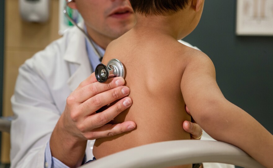 A doctor listens to a child's breathing.