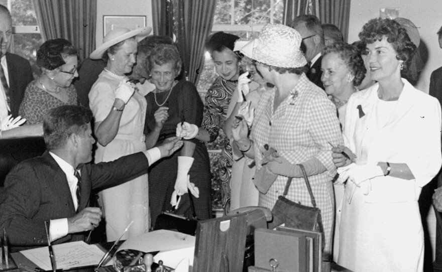 President Kennedy passes out pens on June 10, 1963, after signing the Equal Pay Act.