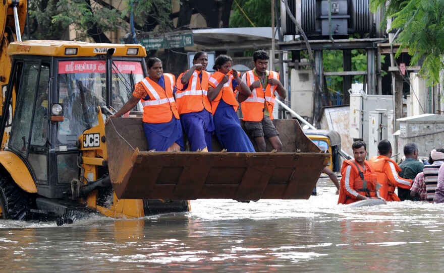 Rescue workers travel in the claw of a bulldozer as they work to rescue stranded residents on Thursday.