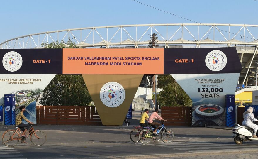 Cyclists cycle past the main entrance of the Narendra Modi Stadium in Ahmedabad, India, a venue where cricket matches were taking place during the 2021 Indian Premier League — until it was suspended.