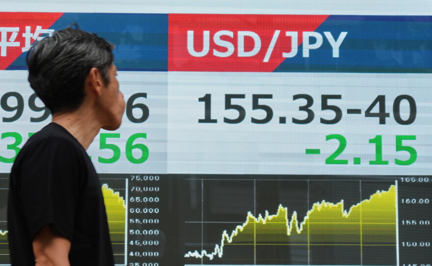 A person walks past an electronic board showing the U.S. dollar and Japanese yen exchange rate at a securities firm in Tokyo on Monday, Aug. 3, 2026.