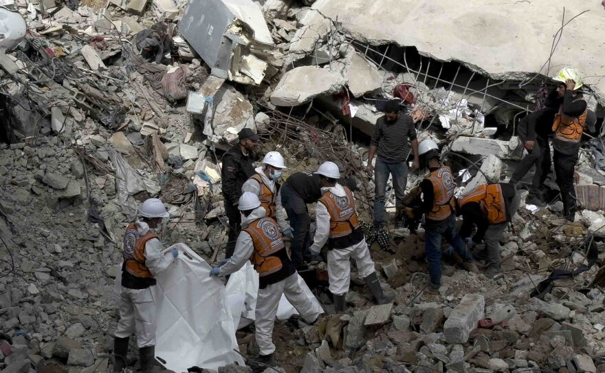 Gaza civil defense crew members carry skeletal remains recovered from beneath the rubble of the Abu Naser family home.