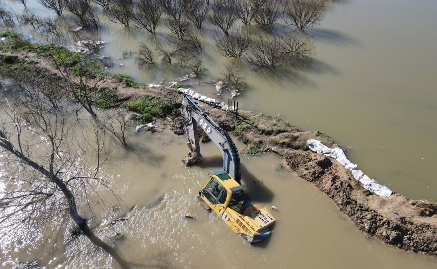 An aerial view shows an excavator lying in a flooded area after the collapse of a dam on the Orontes or Assi river near al-Tulul village in Salqin, in Syria's rebel-held Idlib province.