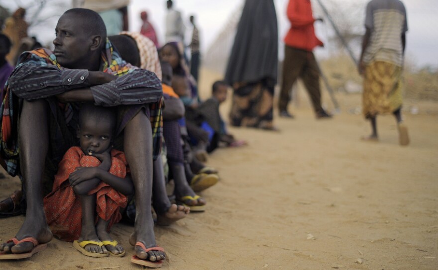 A Somali father sits with his daughter at the head of the line at a refugee camp registration center in Dabaab in northeastern Kenya, Aug. 2, 2011. International aid agencies are struggling to bring in more supplies to drought-stricken Somalia and neighboring Kenya.