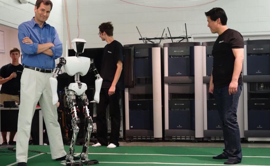 David stands next to CHARLI, a robot built by Dennis Hong (far right) and his students at RoMeLa Lab at Virginia Tech.