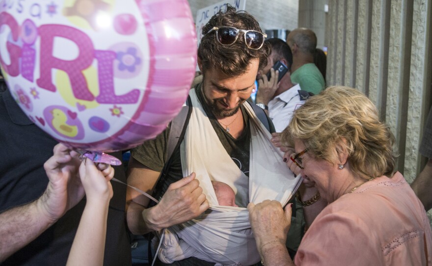An Israeli man carries his newborn baby, who was born to a surrogate mother in Nepal, as he arrives at Ben Gurion airport near Tel Aviv on April 28, after a massive earthquake hit the Himalayan nation. Israel was criticized for evacuating the babies and Israeli parents who had come to pick them up — but leaving the babies' mothers and other pregnant Nepali surrogates behind.