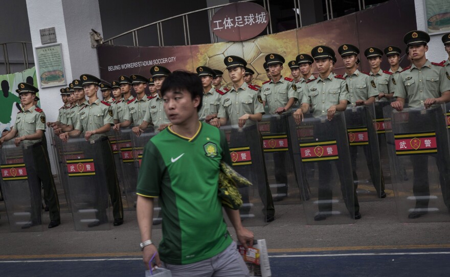A Beijing Guoan supporter passes police officers before a match in 2015. The Chinese government hopes to transform China into a soccer power by mandating soccer programs in schools and investing in the Super League.