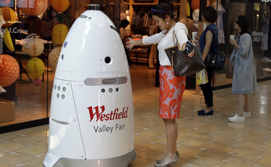 Sophie Li, of Cupertino, Calif., offers to dance with a K5 robot made by Knightscope, Inc., at Westfield Valley Fair shopping center in San Jose, Calif., June 26, 201. 