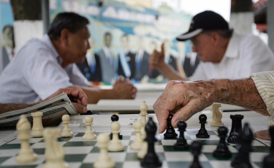 A elderly man makes a move on a chess board at the Maximo Gomez Domino park in Little Havana in Miami, where political opinions are shifting.