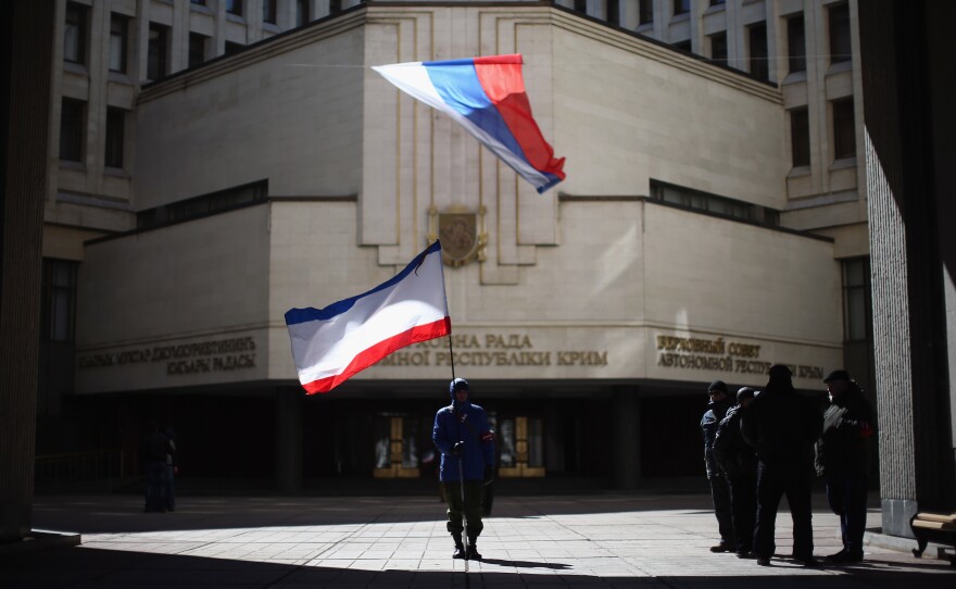 A man holds a Crimean flag in front of the Crimean parliament building on March 17, 2014, in Simferopol, Ukraine. People in Crimea overwhelmingly voted to secede from Ukraine during a referendum vote on March 16 and the Crimean Parliament declared Independence and formally asked Russia to annex them.