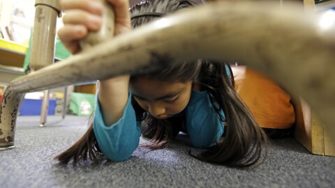 Lillian Zurita shows the proper way to 'drop, cover and hold on' in Ms. Irvin's second-grade class during an earthquake drill known as the Great Shakeout at Rosemont Elementary School near downtown Los Angeles Thursday, Oct. 17, 2013.