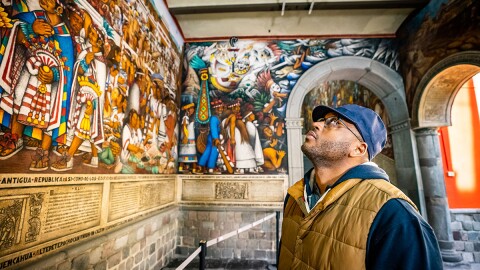 Host Shane Campbell-Staton looking up at "The Gift of Maize" murals at the palace Of The Governor, Tlaxcala, Mexico. From the ~28,000 varieties of Maize that once nurished thounds of cultures across the America's, modern agriculture now only relies on a few varieties that we use in just about every product imaginable.