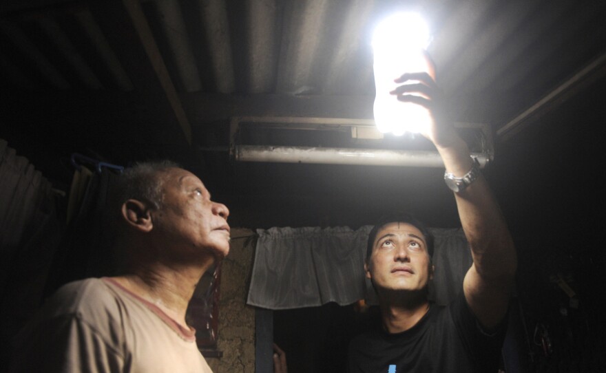 Illac Diaz inspects a solar light bulb with Siplicio Mondas, 73, in Manila. Diaz heads the nonprofit MyShelter Foundation, which is overseeing this solar lighting project.