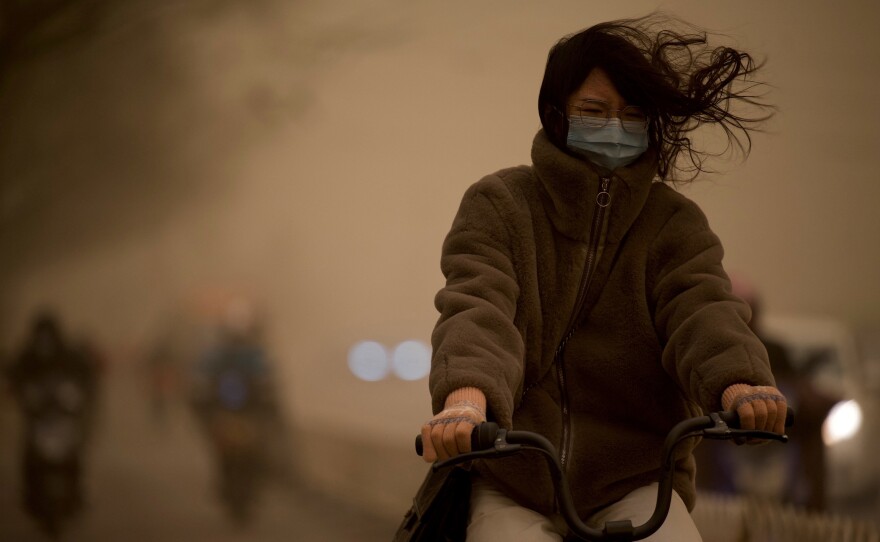 A woman cycles along a street during a sandstorm in Beijing on Monday.