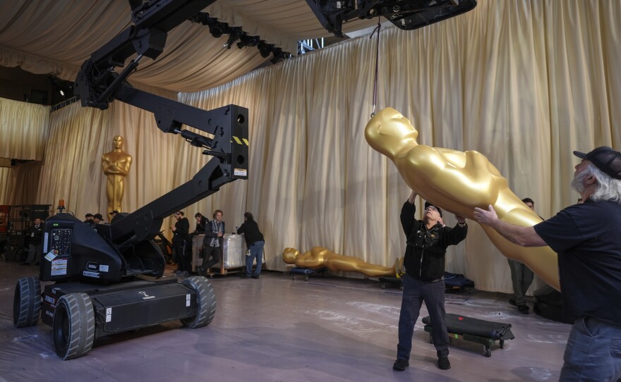 Workers set up an Oscar statue in the red carpet area before the 2025 Oscar awards.