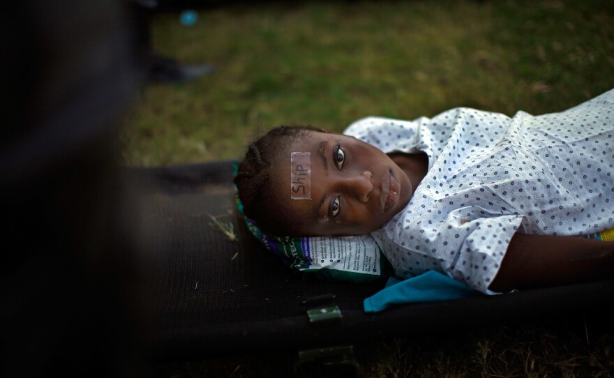 A woman, wearing a tag that identifies her as a transfer patient to the USNS Comfort, waits for a helicopter evacuation in a staging area in front of the National Palace in Port-au-Prince on Jan. 21, 2010.