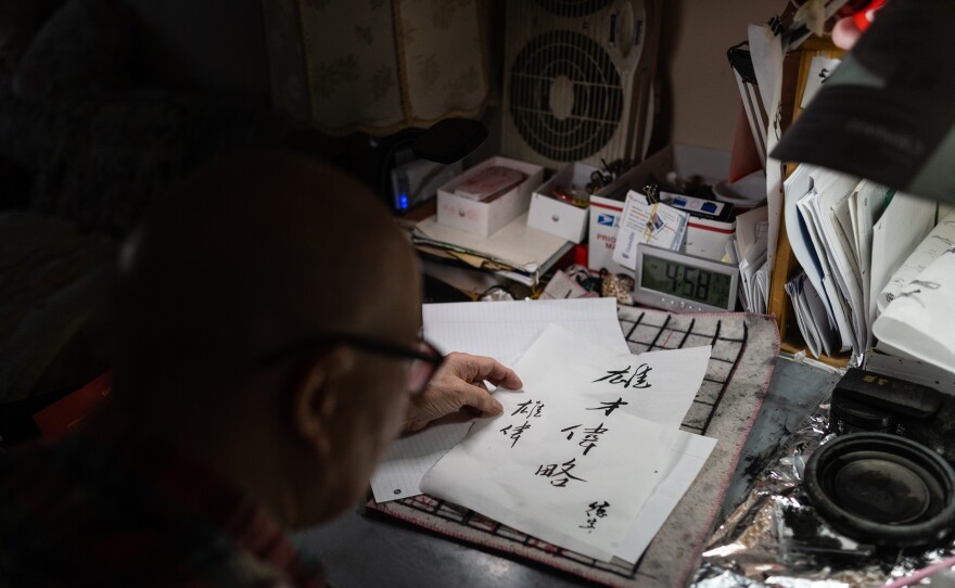 Dock Lee, 90, adds his signature to a calligraphy script with the meaning of Eric Lee's name, "majestic." Eric Lee's grandfather converted a corner of the home into a calligraphy writing set-up where he practices daily.