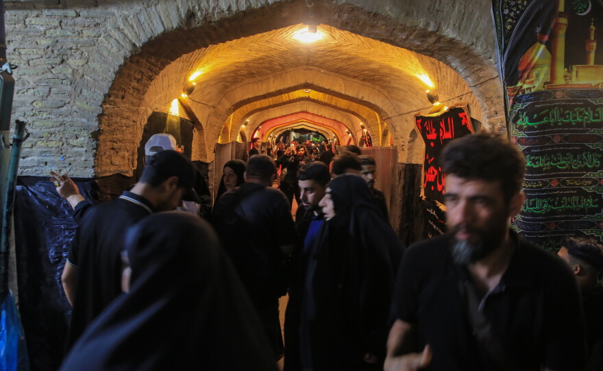 Pilgrims pass through a historic vaulted passage decorated with religious flags and banners in Karbala during the Arbaeen commemoration.