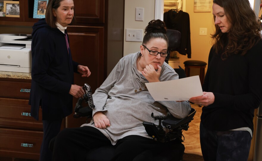 Hogan VanSickle gets help from her sister, Heather Hanson (right), and mother, Clara Brown, as they try to obtain fingerprints for her bar exam application, which is made challenging by the format and the limited mobility in her fingers.