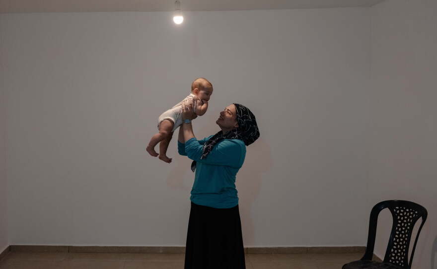 Robin Feldman, a new resident of Sderot, holds her baby inside their newly completed but still unfurnished apartment in Sderot, Israel, Sept. 1, 2026.