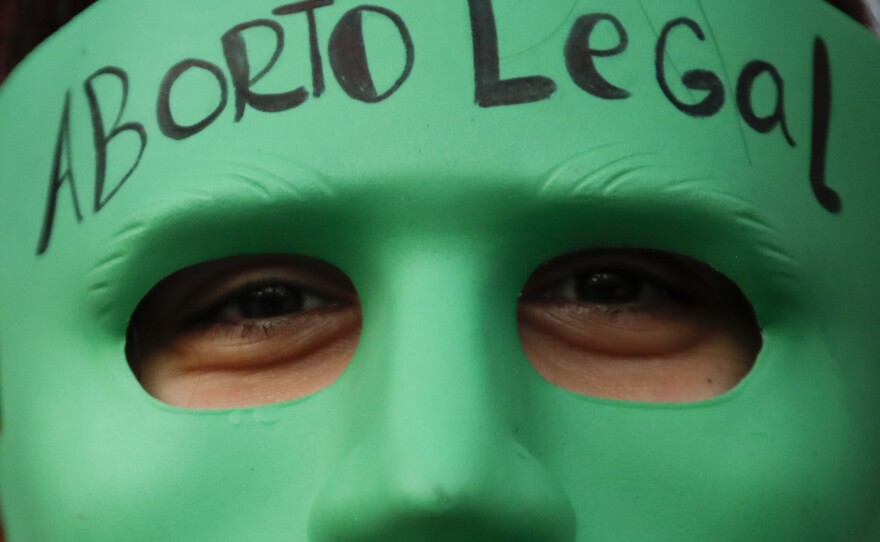 An abortion-rights activist wears a mask with text that reads in Spanish "Legal Abortion" during a rally outside Congress as lawmakers debate a bill that would legalize abortion, in Buenos Aires, Argentina, Tuesday, Dec. 29, 2020.