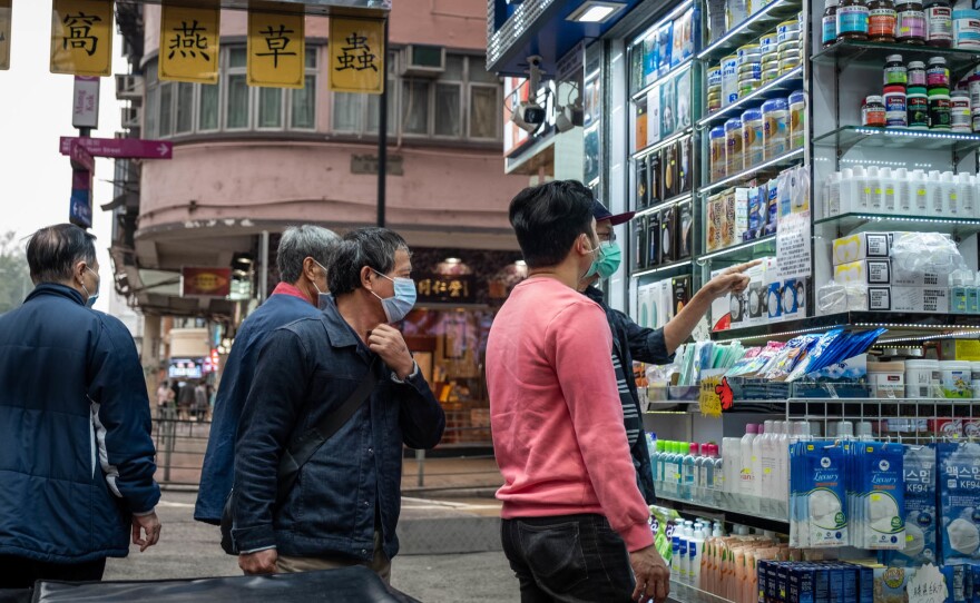 People inspect surgical masks for sale. Hong Kong health authorities have encouraged people to wear masks to control the spread of the novel coronavirus. Some stores have increased the price because of demand.