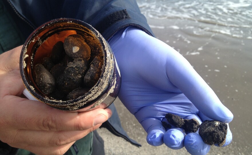 Jonathan Henderson of the Gulf Restoration Network holds a jar of tar balls.