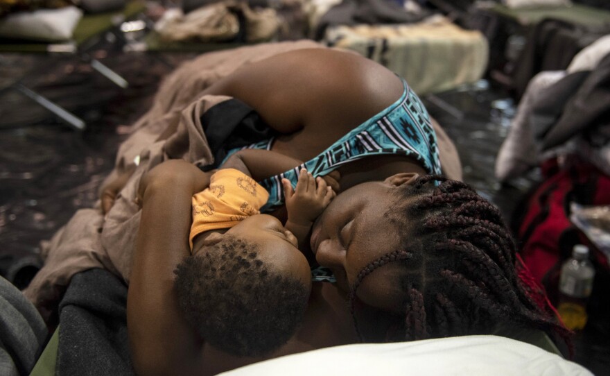 A woman holding a child sleeps at Southeast Raleigh High School in Raleigh, N.C., on Wednesday after being evacuated from her home ahead of Hurricane Florence.