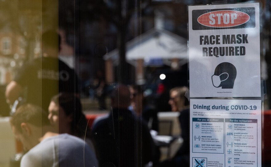 A sign requiring face masks and COVID-19 protocols is displayed at a restaurant in Plymouth, Mich., on March 21. Coronavirus cases in Michigan are skyrocketing after months of steep declines, one sign that a new surge may be starting.