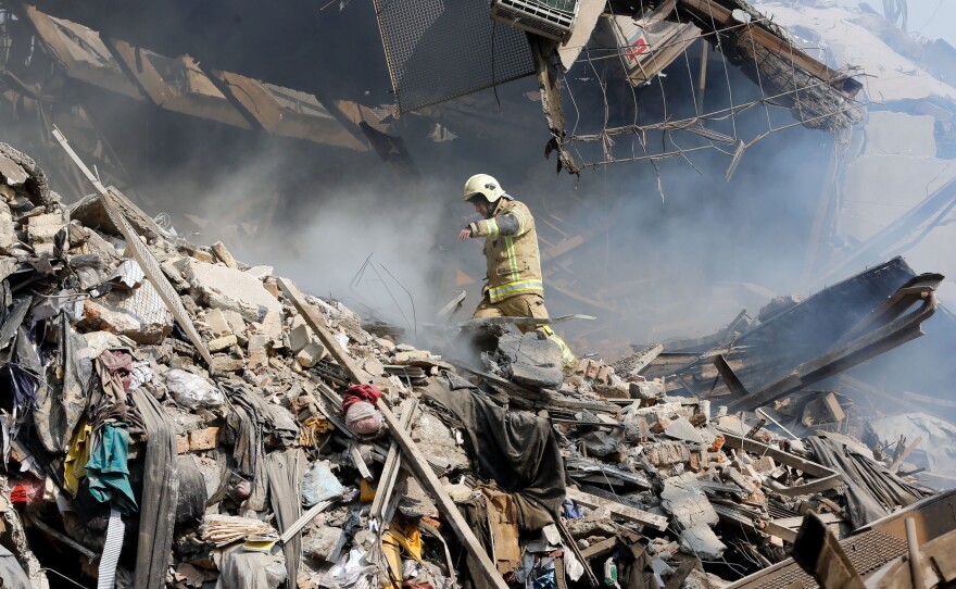 An Iranian firefighter walks amid the debris of Tehran's 17-story Plasco building after it became engulfed in flames and collapsed Thursday.