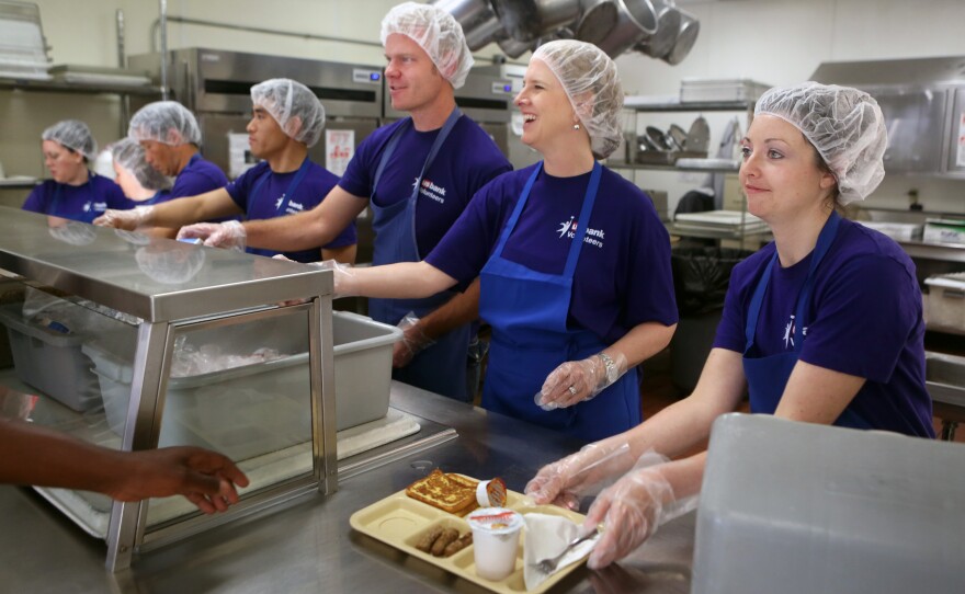 Kristin Yentes (right) and other volunteers from U.S. Bank serve breakfast to diners at Catholic Charities Opportunity Center in Minneapolis. Workers from the bank have been volunteering with Catholic Charities for more than a year.