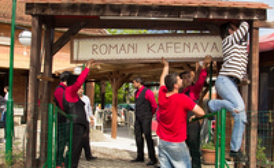 Workers hang the sign at Romani Kafenava ahead of the restaurant's opening.