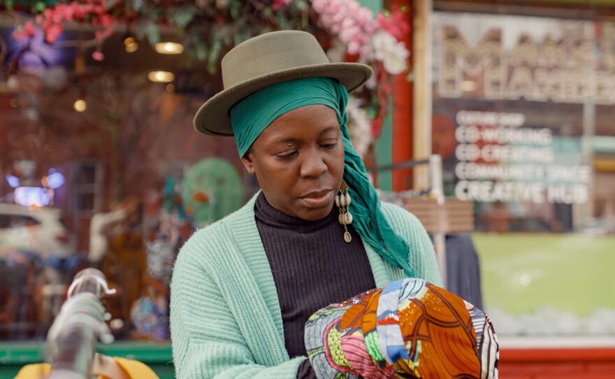 Hekima Hapa hangs clothing items outside her shop.
