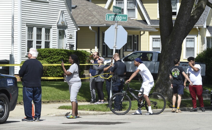 Law enforcement officers and onlookers fill the street outside Graceland Cemetery in Racine, Wis., after a shooting on Thursday.