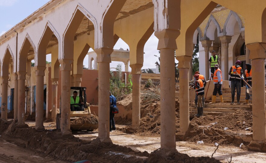 Workers move piles of mud and dirt outside a Derna mosque following fatal floods, Sept. 18.