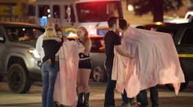 People comfort each other as they stand near the scene Thursday, Nov. 8, 2018, in Thousand Oaks, Calif. where a gunman opened fire Wednesday inside a country dance bar crowded with hundreds of people on "college night," wounding 11 people including a deputy who rushed to the scene.