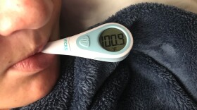 A boy with the flu takes his temperature at his home in San Diego, Feb. 14, 2018.
