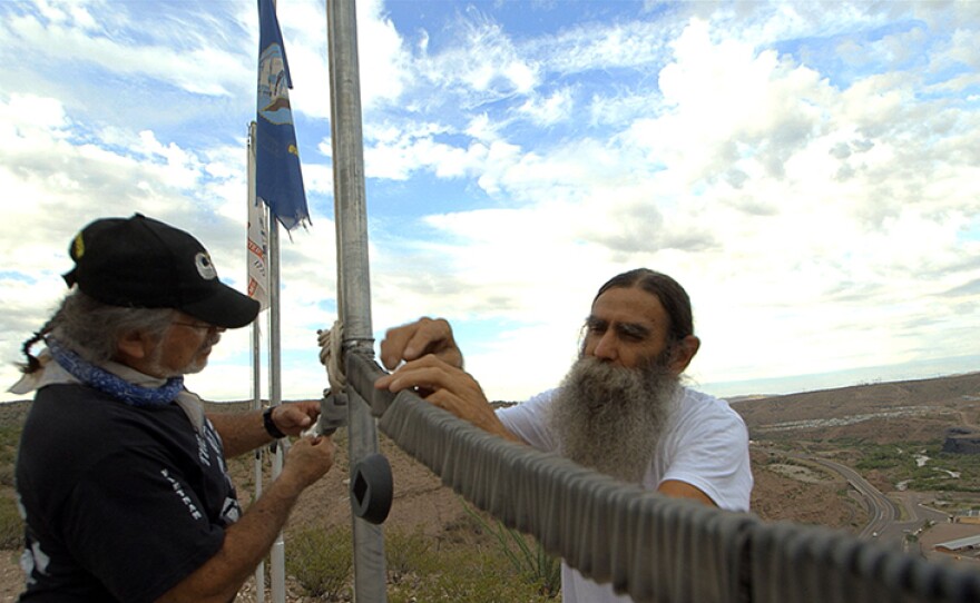 Vietnam veterans Oscar Urrea and Steve Guzzo inspect some of the more than 2,000 replica dog tags on the Mares Bluff Veterans Memorial in Clifton, Ariz.