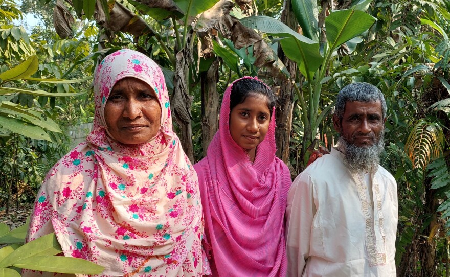 Rahima Banu outside her home with her daughter and husband.