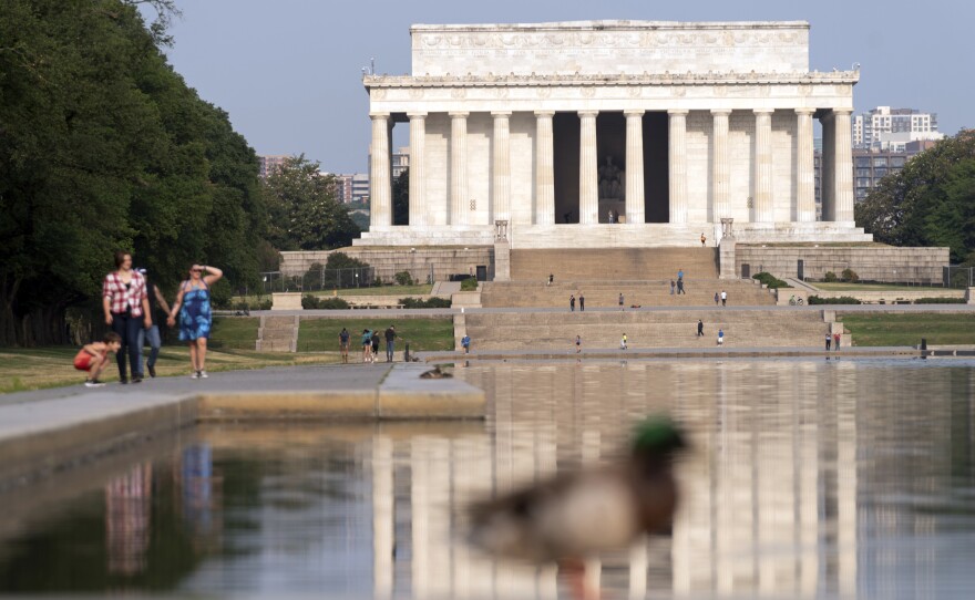 With a blue sky above the Lincoln Memorial, people walk along the reflection pool in Washington, D.C., on June 9, 2023.