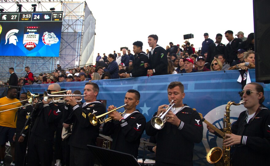 A Navy band plays as fans cheer behind them during the Armed Forces Classic on board USS Abraham Lincoln in San Diego on Nov. 11, 2022.