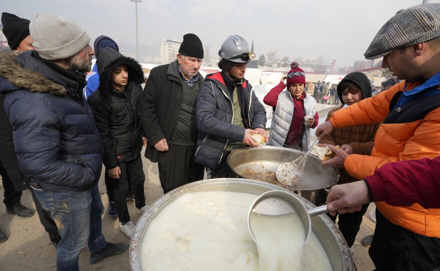 People wait for a meal at a stadium where tents have been setup to accommodate earthquake survivors, in Kharamanmaras, southeastern Turkey. Rescuers pulled several people alive from the shattered remnants of buildings on Friday, some who survived more than 100 hours trapped under crushed concrete in the bitter cold.