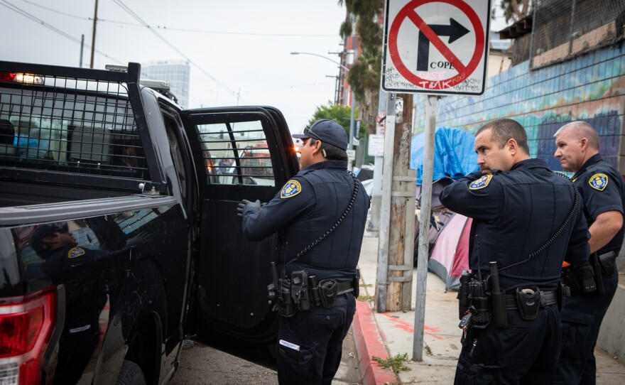 San Diego police detain a person who they say has an outstanding warrant during an enforcement sweep on Commercial Street in San Diego, June 9, 2022.  