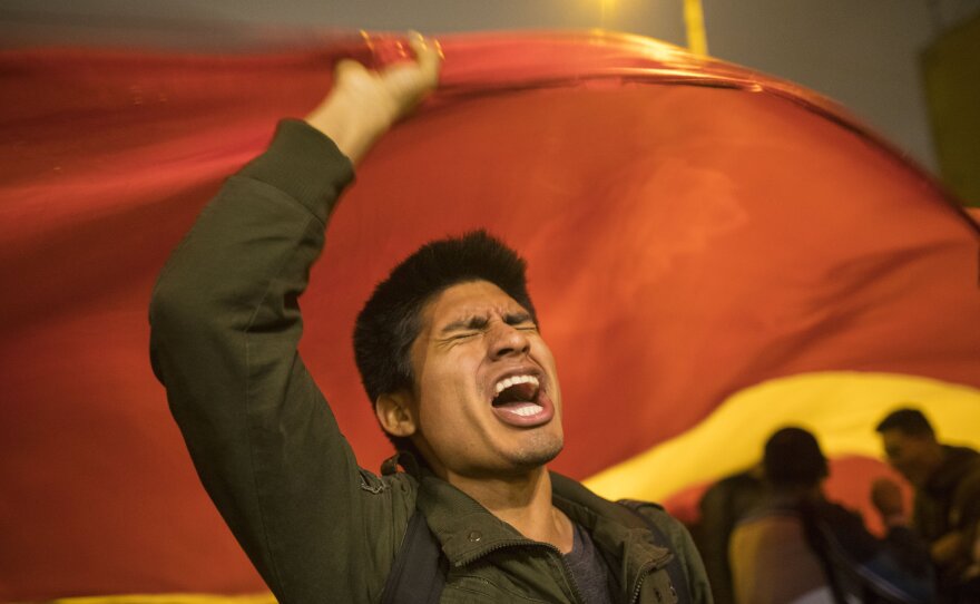 A supporter of Peruvian President Martín Vizcarra chants slogans outside the legislature building in Lima on Monday night, not long after Vizcarra dissolved Congress. Opposition lawmakers defied the president's order and voted to suspend him from office.