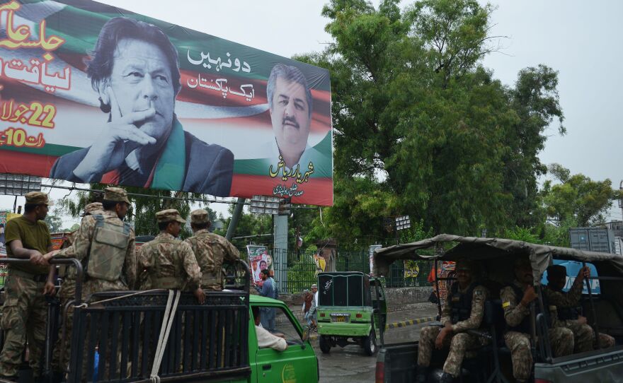 Pakistani soldiers patrol on a street beside a billboard featuring an image of Imran Khan of the Pakistan Tehreek-e-Insaf (Movement for Justice), in Rawalpindi.