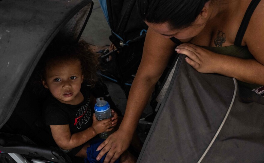 A woman wipes her son with a wet cloth as her family waits at a bus station in Tucson, Ariz. On Wednesday, Tucson set a new record for consecutive days of 100-plus-degree temperatures with 40, dating back to June 16.