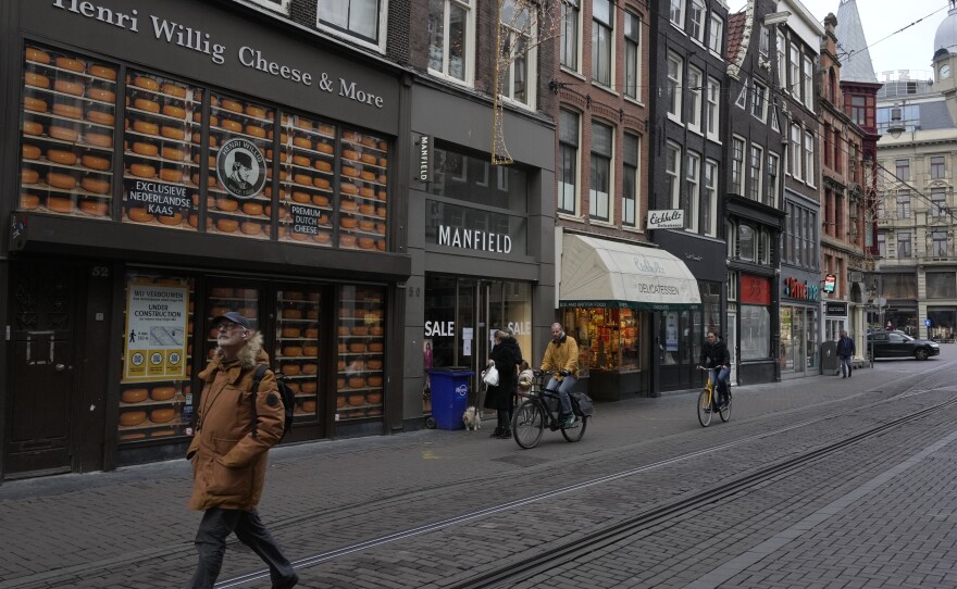 A man walks by a closed cheese store on a normally bustling shopping street in the center of Amsterdam on Monday. Nations across Europe have moved to reimpose tougher measures to stem a new wave of COVID-19 infections spurred by the highly transmissible omicron variant. Netherlands has imposed a nationwide lockdown.