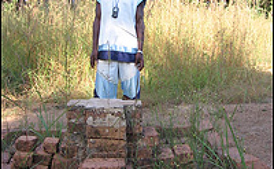 Valentin Ilunga stands at a brick memorial erected for Lumumba, who was buried with two other men in a shallow grave at this site. The bodies were later removed and destroyed.