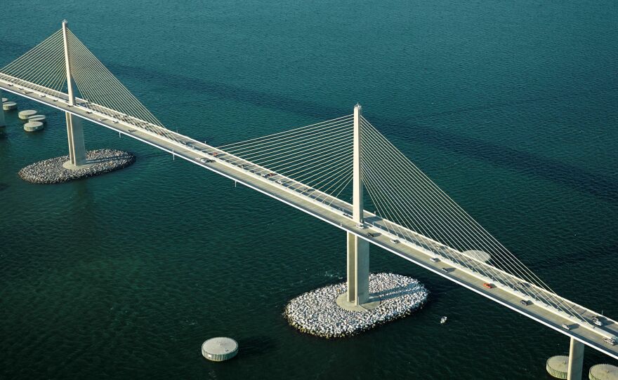 An aerial photo of the Sunshine Skyway Bridge over Tampa Bay in Florida shows both artificial islands surrounding pylons and circular concrete dolphins used as protection against collisions with large vessels.